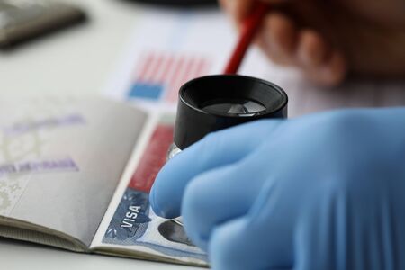 Specialist with loupe checking authenticity of american visa in passport close-upの写真素材
