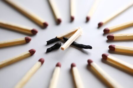 Broken burned out match in surrounded by evil intact fellows close-up. Dominance and cruelty among people conceptの写真素材