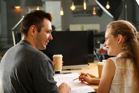 Portrait of successful team talking about profitable project at work. Young friendly male smiling to...