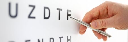 Silver ballpoint pen pointing to letter in eyesight check table. Sight test and correction excellent vision or optician shop laser surgery alternative driver health certificate examination conceptの写真素材