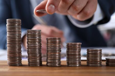 Close-up view of businessman putting penny on staircase of coins. Symbol of financial growth and...