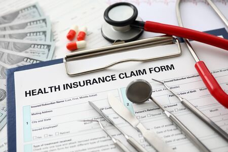 Silver dentist tools lying on application form at insurance agent worktable in company office...