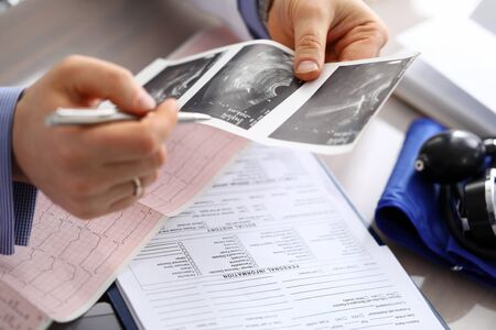 Doctor compares cardiogram, ultrasound diagnosis. Doctor determines amount additional diagnosis...