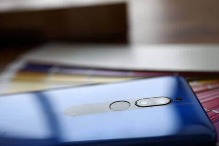 Modern blue smartphone lying at colorful fantail close-up