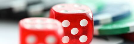 Red dices lying with casino chips as gambling symbol close-up