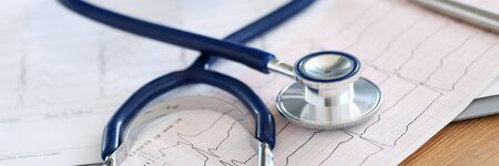 Medical stethoscope twisted in heart shape lying on cardiogram chart closeup. Medical help, prophylaxis, disease prevention or insurance concept. Cardiology care, health, protection and preventionの写真素材