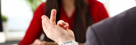 Young businessman in official clothing sitting in office, talking with woman colleague and gesticulating with fingers. Business people, negotiations, people working in office conceptの写真素材
