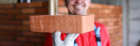 Smiling male builder showing fine quality brick material in camera close-upの写真素材