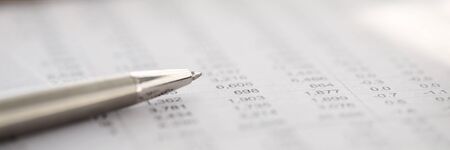 Stylish silver pen rests on report with numbers. Interest potential customers through social site research. Determine composition companys marketing activities for sales promotion and pricingの写真素材