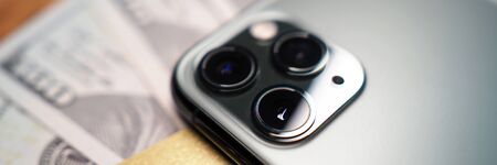 Turned over cellphone lying at bunch of US dollars close-up