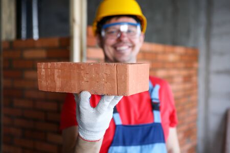 Smiling male builder showing fine quality brick material in camera close-upの写真素材
