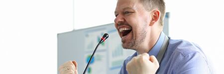 Male speaker clenched his fists front microphone. Business coach is working on developing practical skills. Audience develops confidence in speaker. Center for oratory and negotiationの写真素材