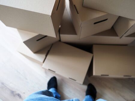 Male legs standing near huge pile of cardboard boxes close-up