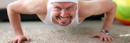 Close-up of man doing push-ups indoors on quarantine. Sport for fit body and muscles. Pink dumbbells...