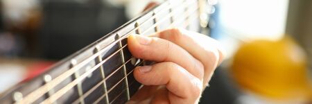Close-up of persons hand playing on acoustic guitar. Macro shot of male performing beautiful melody...