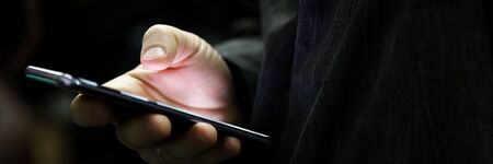 Close-up of man using mobile phone for searching information in internet. Persons hand holding...