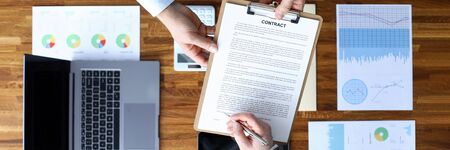 Men sign contract on background documents devices. Source information for persons directly...
