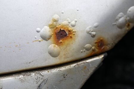 Close-up of rusty car covered with corrosive defect of iron. Macro shot of old automobile and cracking white colour paint. Scratch on auto. Vehicle and transport conceptの写真素材