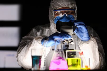 Close-up of concentrated chemists working with glass flasks filled with colourful liquids....