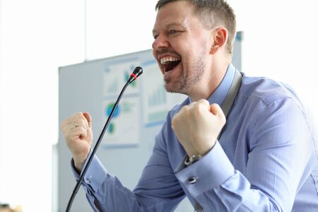 Male speaker clenched his fists front microphone. Business coach is working on developing practical skills. Audience develops confidence in speaker. Center for oratory and negotiationの写真素材