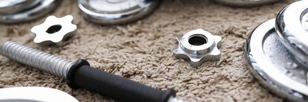 Pile of shiny chrome dumbbells disks lying around grip at home rug as domestic sport exercises during coronavirus quarantine period close-upの写真素材
