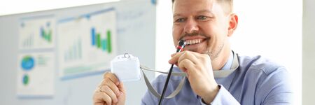 Close-up of handsome man looking away with gladness and smile. Smiling businessman showing badge...