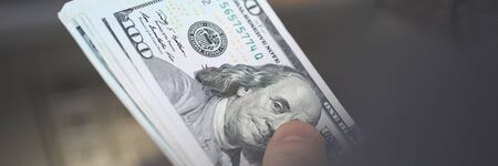 Close up dollars, hand holds bundle banknotes. Man stand near terminal and withdraws cash dollars....