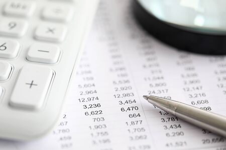 Silver pen report with numbers next to calculator. Range financial instruments for trading on...