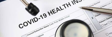 Silver pen lying at covid-19 insurance claim blank ready to be filled close-upの写真素材