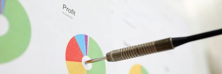 Dart sticking out from financial diagram as profit pursuit symbol close-up