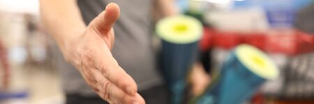 Guy in sportswear holds out his hand for a handshake. A sports store consultant welcomes a customer. Purchase of sports equipment for fitnessの写真素材
