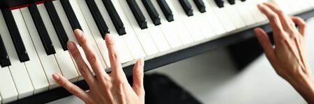 Close-up female hands lie on the keys of a digital piano. Live broadcast of a music program during quarantine. solfeggio trainingの写真素材