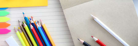 Top view of colourful set of pencils for drawing. Empty sheet on table. Pins with bright covers and...