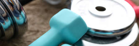 Pile of shiny chrome dumbbells disks lying around grip at home rug as domestic sport exercises...