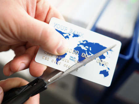 Male hand cutting banking card with scissors closeup