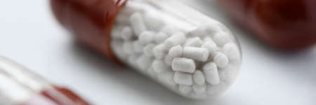 Close-up of red and white pill on table. Meds for faster recovery. Care for ill adult. Tablet to...