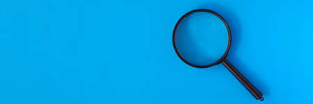 Top view of black magnifying glass on blue pastel background. Loupe for better vision. Minimal design. Exploration. Copy space in left side. Zoom and lens conceptの写真素材