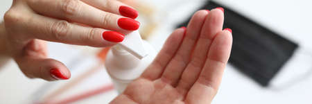 Close-up of female pressing moisturizing lotion on hand. Woman smoothing hands. Beautiful bright red manicure. Taking care of skin. Beauty and cosmetics conceptの写真素材
