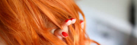 Close-up of female touching red hair. Woman with beautiful fresh manicure. Pretty curls on head. Good volume and waves after curling iron. Cute hairstyle. Beauty conceptの写真素材