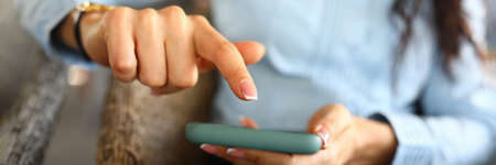 Close-up of businesswoman working in modern smartphone. Businesslady flipping news on cellphone....