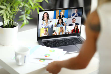 Woman talking with international colleagues using online video chat service at workplace closeup