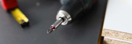 Close-up of worker instruments. Drill and roulette on black wooden surface. Equipment for work....