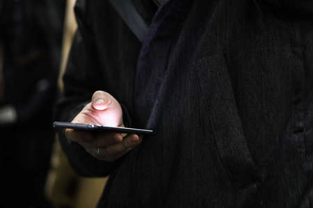 Close-up of hands of person using mobile phone at night. Light of smartphone screen in evening....