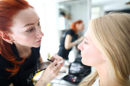 Portrait of stylist and client in beauty salon. Professional care for skin, makeup and hair in...