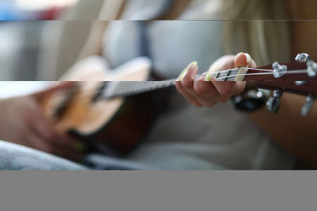 Close-up of adult person holding acoustic guitar and playing melody. Female hand placed on string. Spare time and leisure. Talented woman. Music and hobby conceptの写真素材
