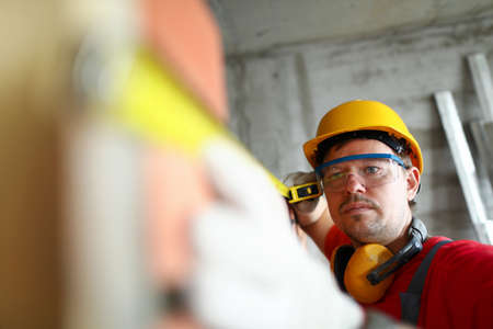 Portrait of builder with measuring tape. Foreman checking quality of work, man with tool for looking...