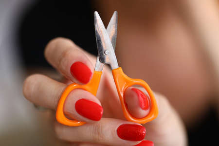 Close-up of woman holding and showing on camera small orange scissors for comfy tailor work....