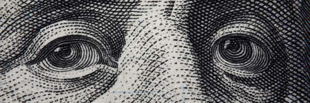 Close-up of benjamin franklins face on hundred banknote. Macro shot of grey facial composition of...