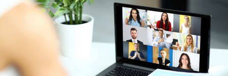 Woman talking with international colleagues using online video chat service at workplace closeup