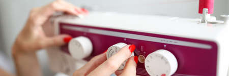 Close-up of female hands adjust the relay on the sewing machine. Maintenance of equipment in a...